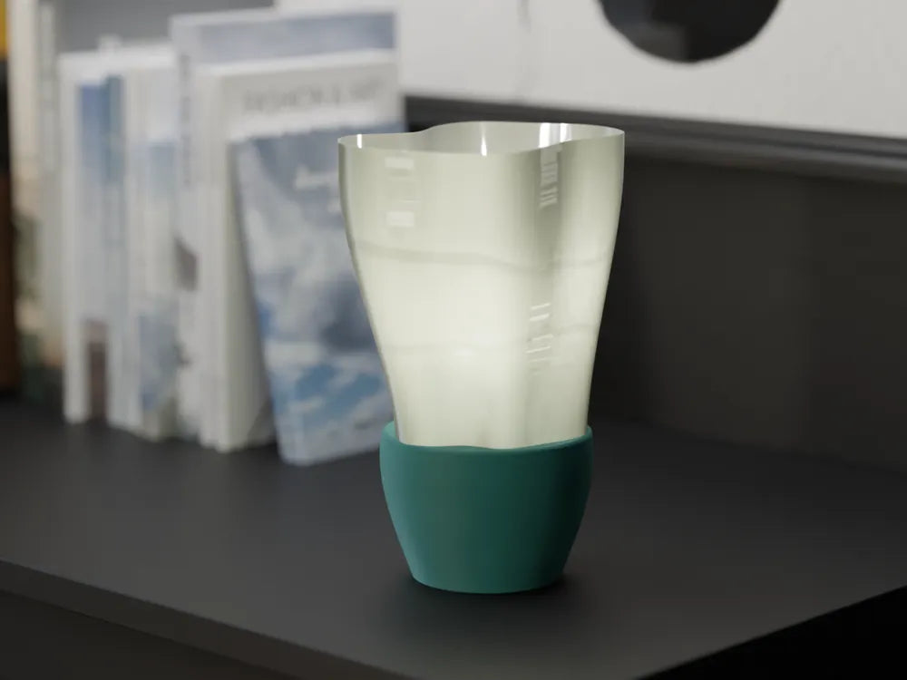 The Flowing E14 Lamp's flowing white shade and green base on a dark shelf with books