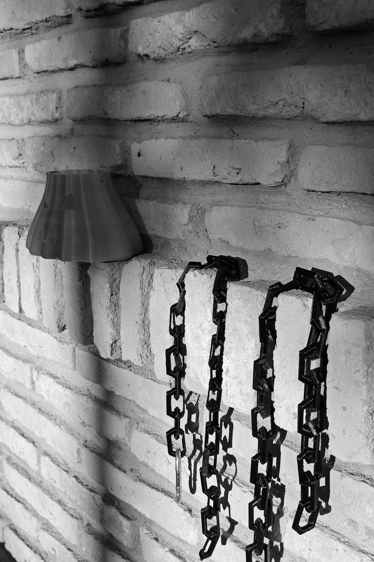 Chained pumpkin bag with black linked chains hanging against a brick wall