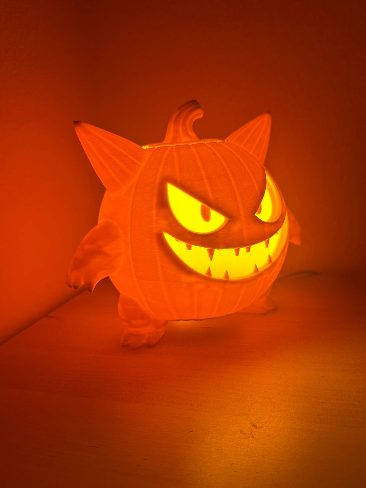 Monster Pumpkin Tealight Holder — side three-quarter glow shot showing amber light effect and full figure silhouette against orange background