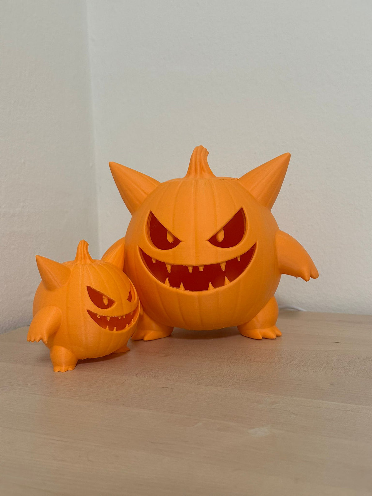 Monster Pumpkin Tealight Holder — three-quarter angle glow shot showing amber light through carved face and arm detail against orange background