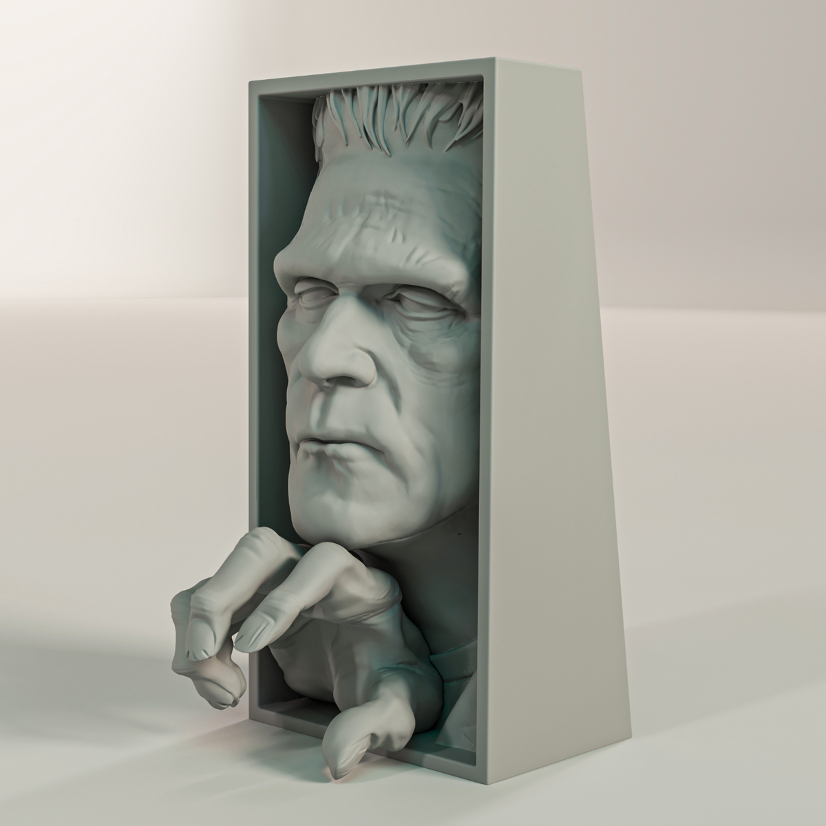 Frankenstein monster relief sculpture grey matte rectangular framed box deeply modelled face heavy brow bolt neck hair grasping clawed hand reaching forward three quarter angle view neutral background showing full three dimensional depth of the framed box form