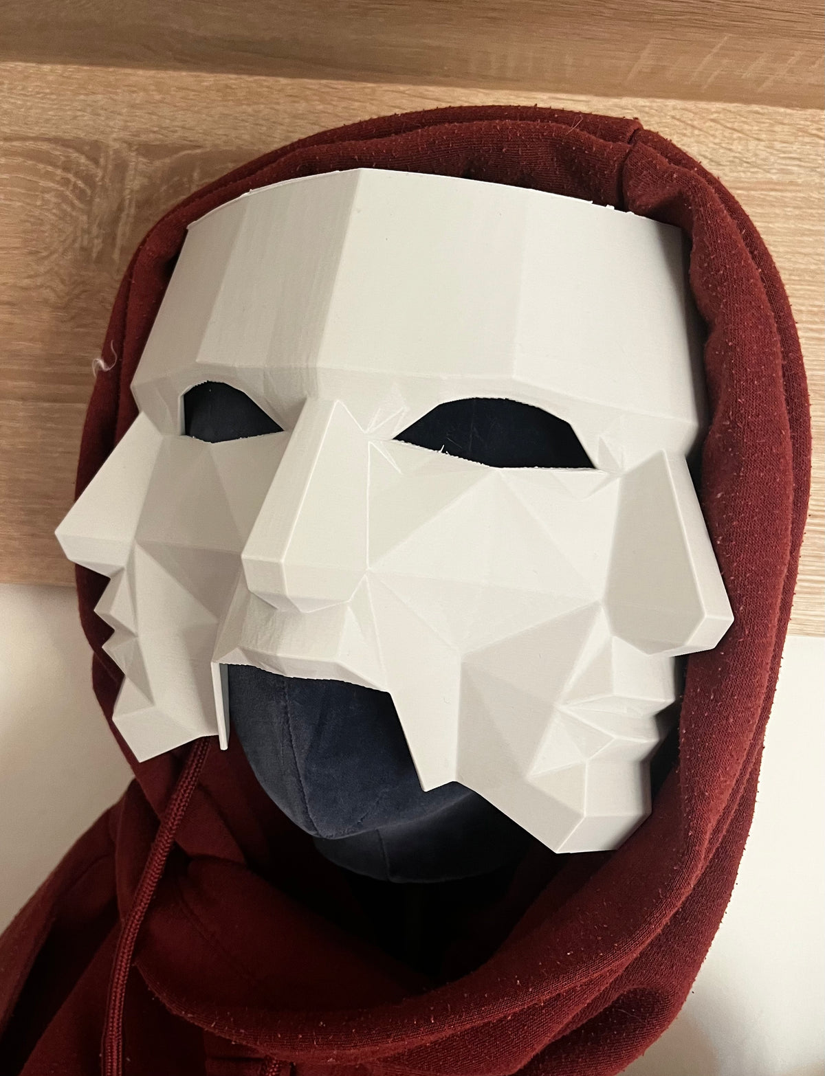 Three Faces of Fear Mask worn with crimson red hood — lifestyle shot