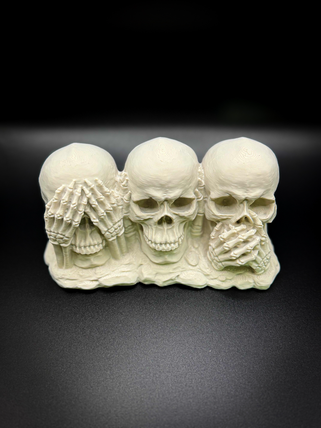 See No Evil Hear No Evil Speak No Evil Skull — front view showing three cream skulls with skeletal hands covering eyes, ears and mouth on shared rocky base