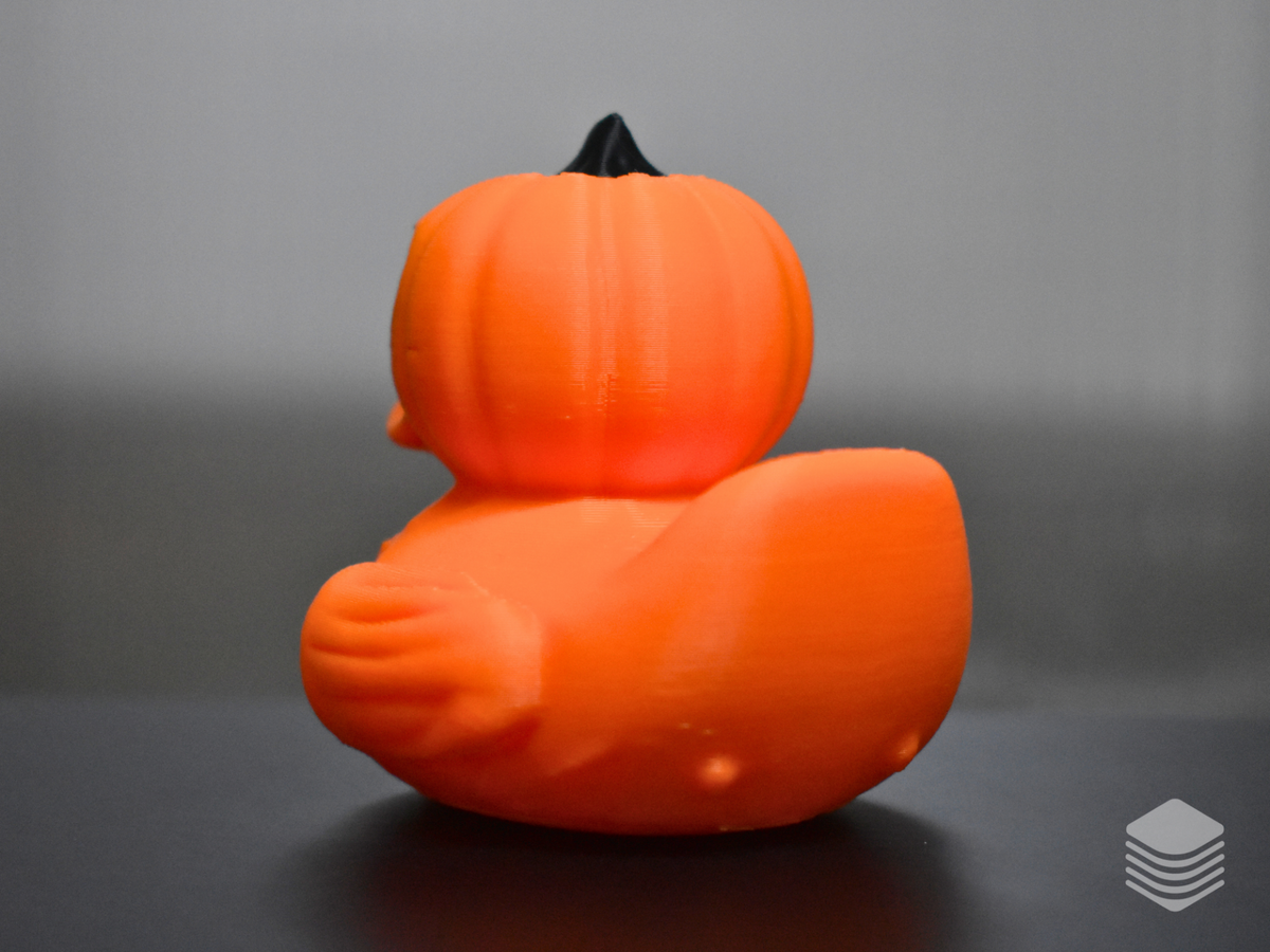 Halloween Pumpkin Duck — rear full view: vivid orange rounded body with vertical pumpkin lobe divisions, pumpkin head from rear with lobe lines and black stem tip, orange tail form, wing forms with lobe detail at both sides