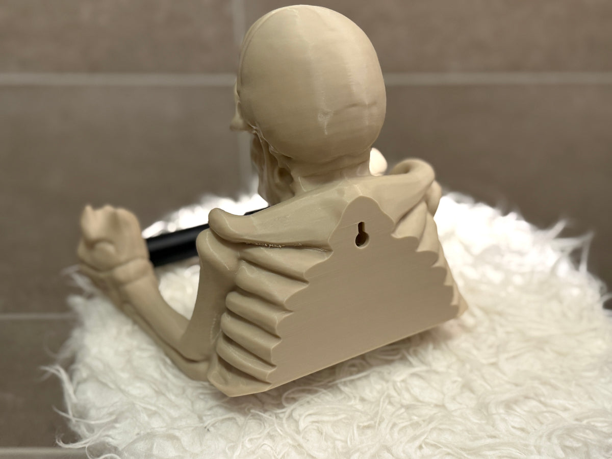 Skeleton toilet roll holder white bone colour rear view showing keyhole wall mount bracket full spine and ribcage rear detail on white fluffy surface installation reference shot