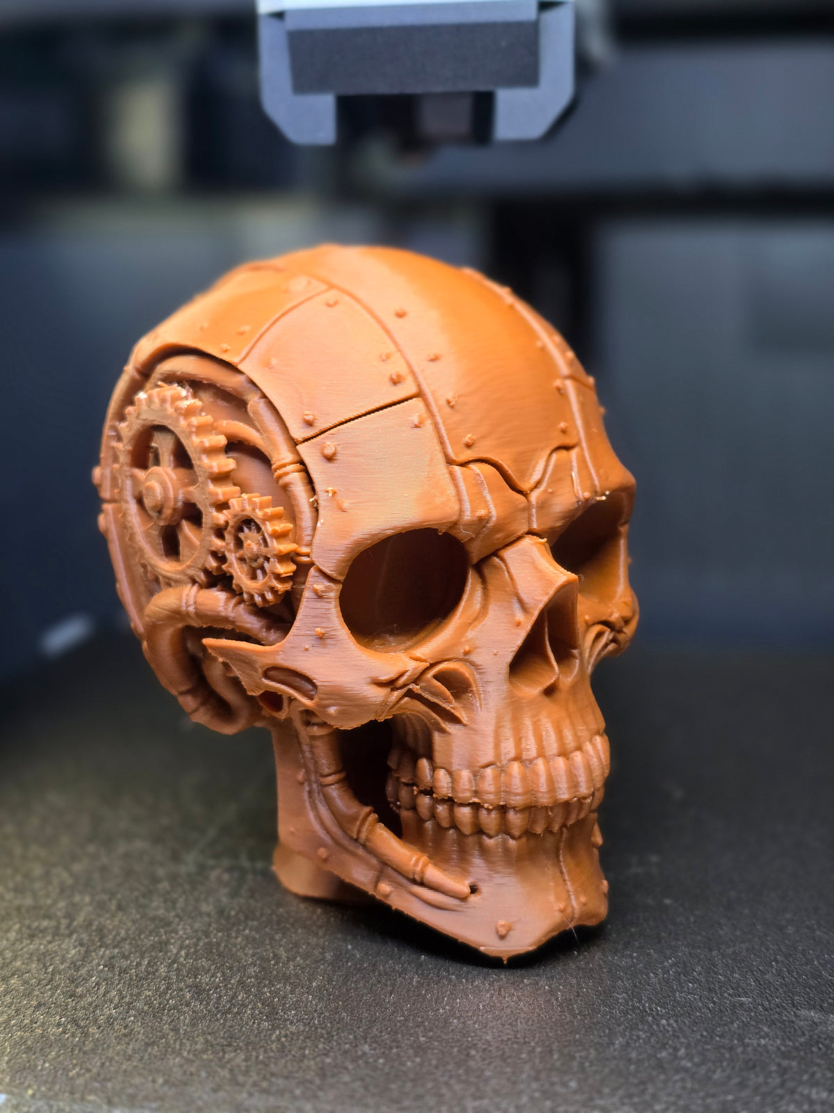 Steampunk Gear Skull Sculpture — three-quarter rear view showing large primary gear, secondary cogs and riveted panel plating across cranium