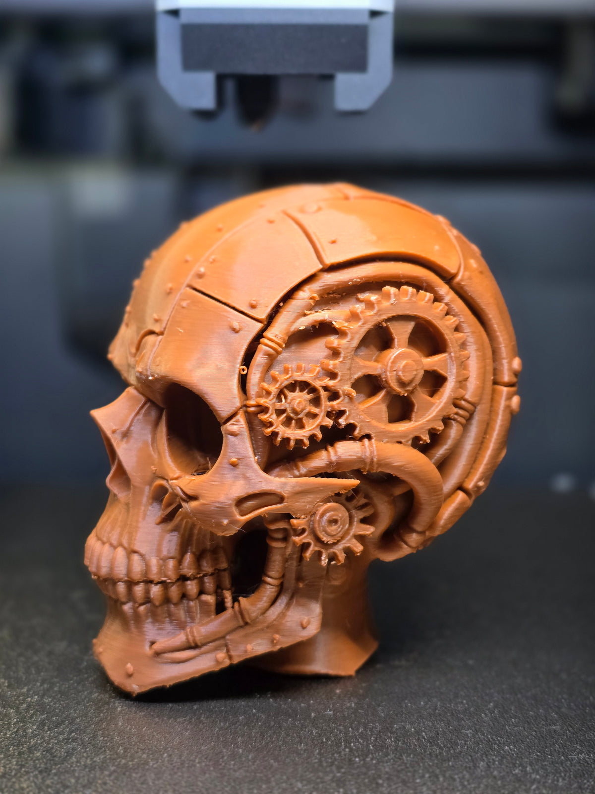 Steampunk Gear Skull Sculpture — front three-quarter view showing full gear train detail in temporal window, riveted plating and jaw mechanical detail