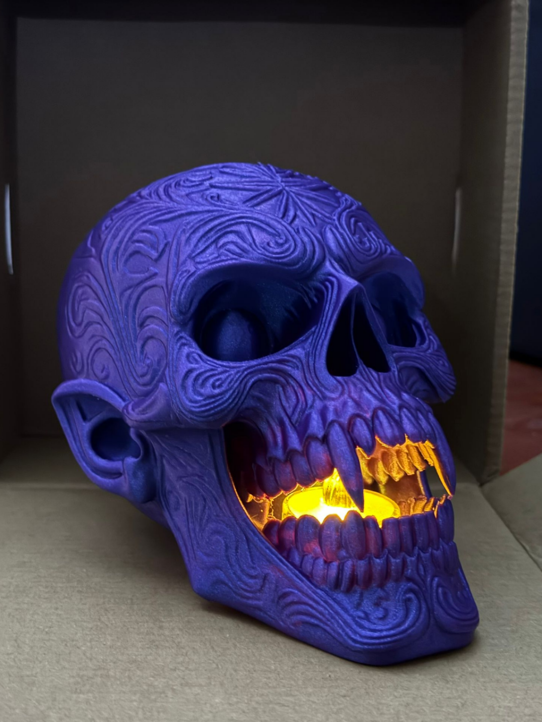 Skull Tealight Holder in purple — front view showing filigree detail and amber bat glow through jaw
