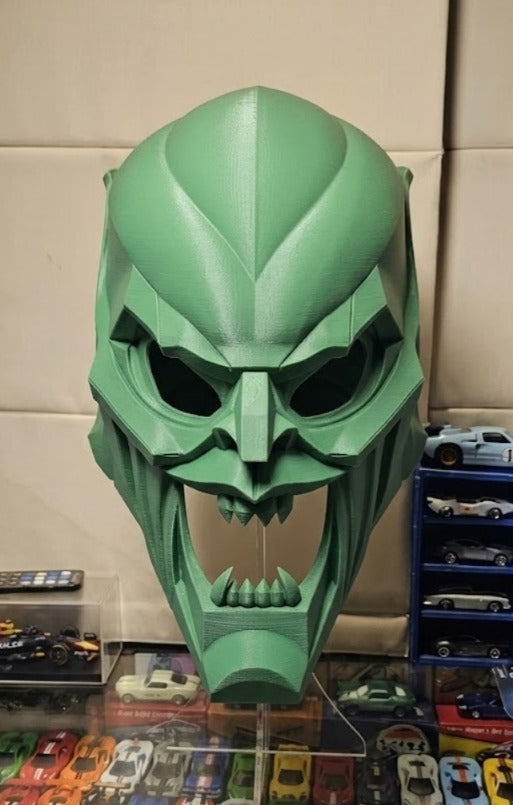 Geometric Villain Horror Mask Sculpture in green — second front view on clear acrylic stand showing full geometric panel faceting across cranial dome, brow overhang, eye section depth, nose bridge and open lower fang jaw
