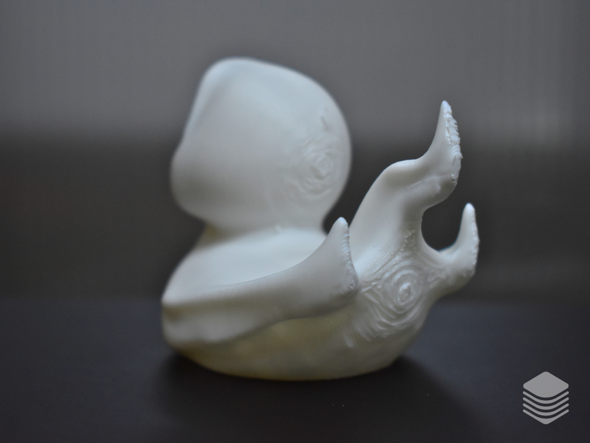Halloween Ghost Duck Sculpture — rear left view: pure white ghost sheet rear, large flame-form sheet drapes extending from rear body with upward-curling tips, sculpted organic wing forms with spiral scroll detail visible beneath ghost sheet at rear body