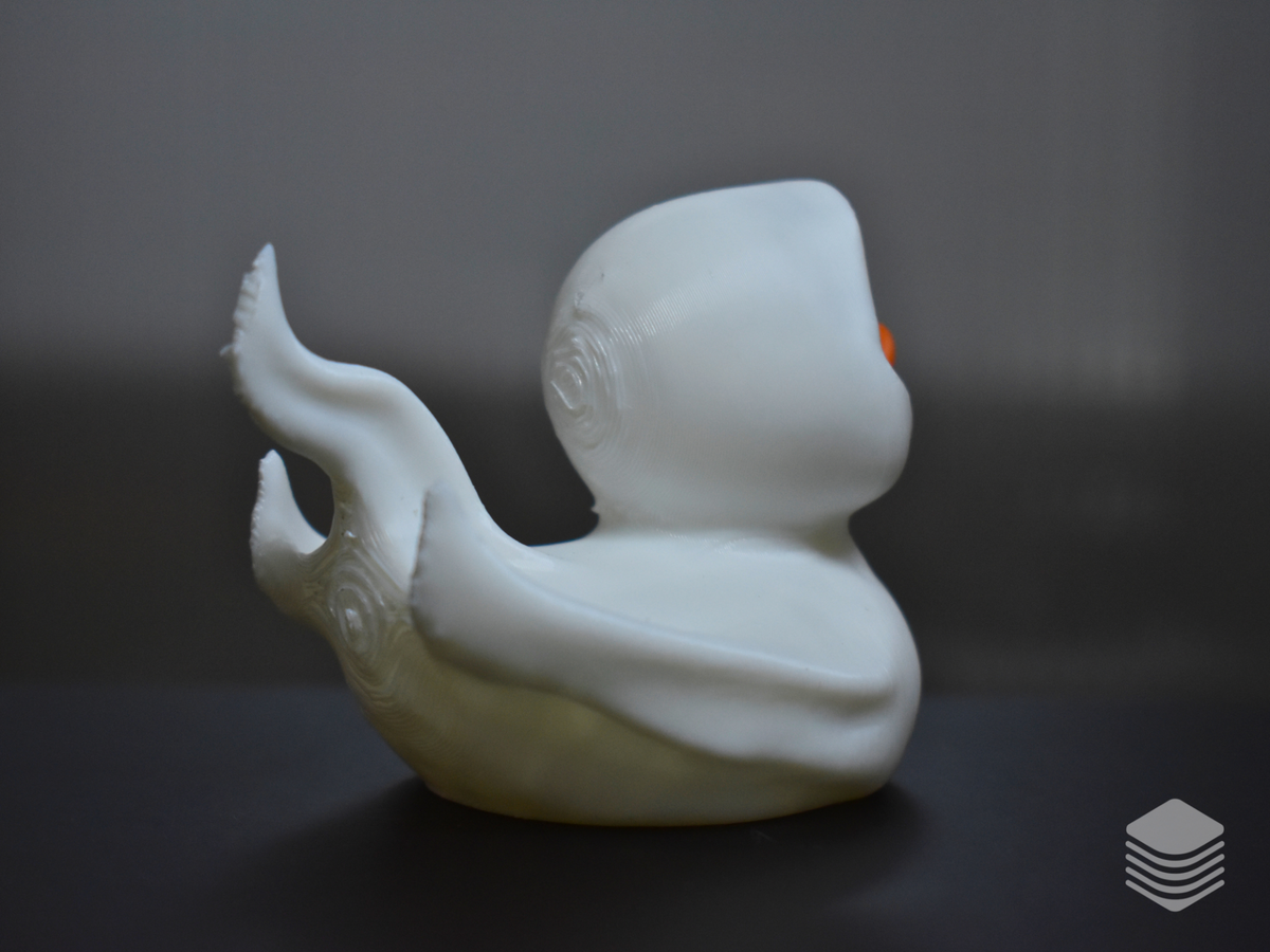 Halloween Ghost Duck Sculpture — right rear three-quarter view: ghost sheet flame drapes from rear right angle with upward-curling tips, sculpted organic spiral scroll wing detail beneath ghost sheet visible at rear body, orange bill visible at right face edge