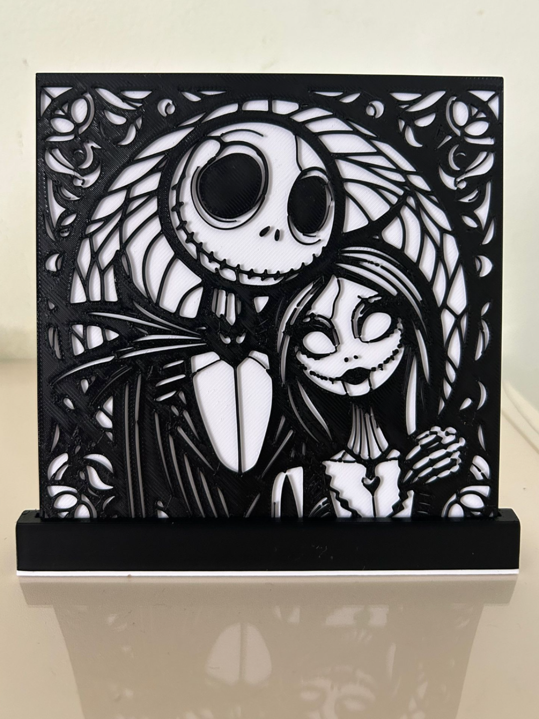Jack & Sally Nightmare Before Christmas Shadow Box Display — front view showing black filigree overlay of Jack Skellington and Sally portrait with dense Halloween foliage border mounted over white backplate in black desktop stand