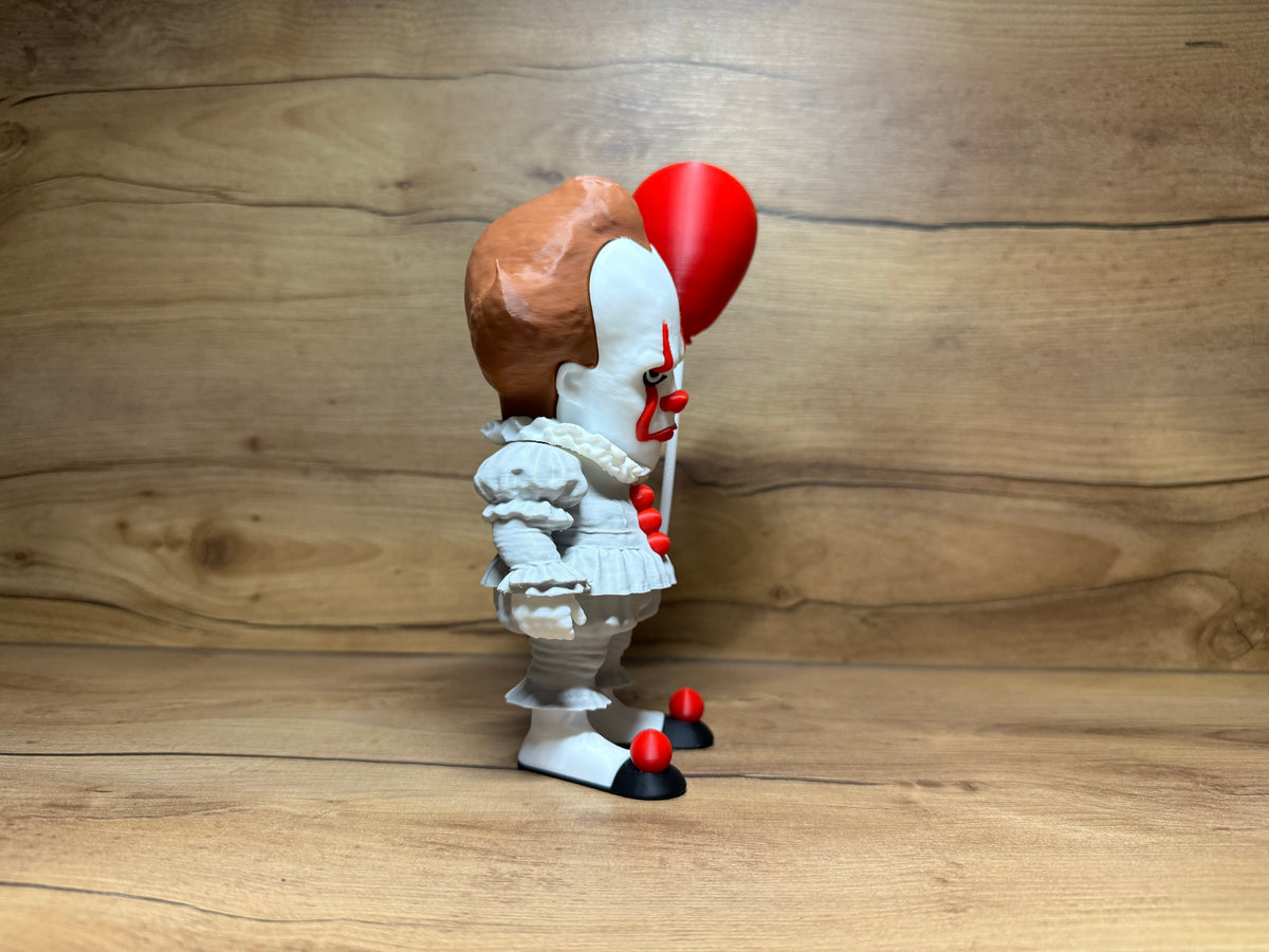 Pennywise IT Horror Minifigure Sculpture — right side full profile view showing auburn hair tuft volume and bald crown dome profile, single visible yellow-gold eye, white collar disc depth from side, right arm forward holding red balloon on white stick string, white ruffled waist skirt tier profile, white puffed leg form and black shoe with red pompom