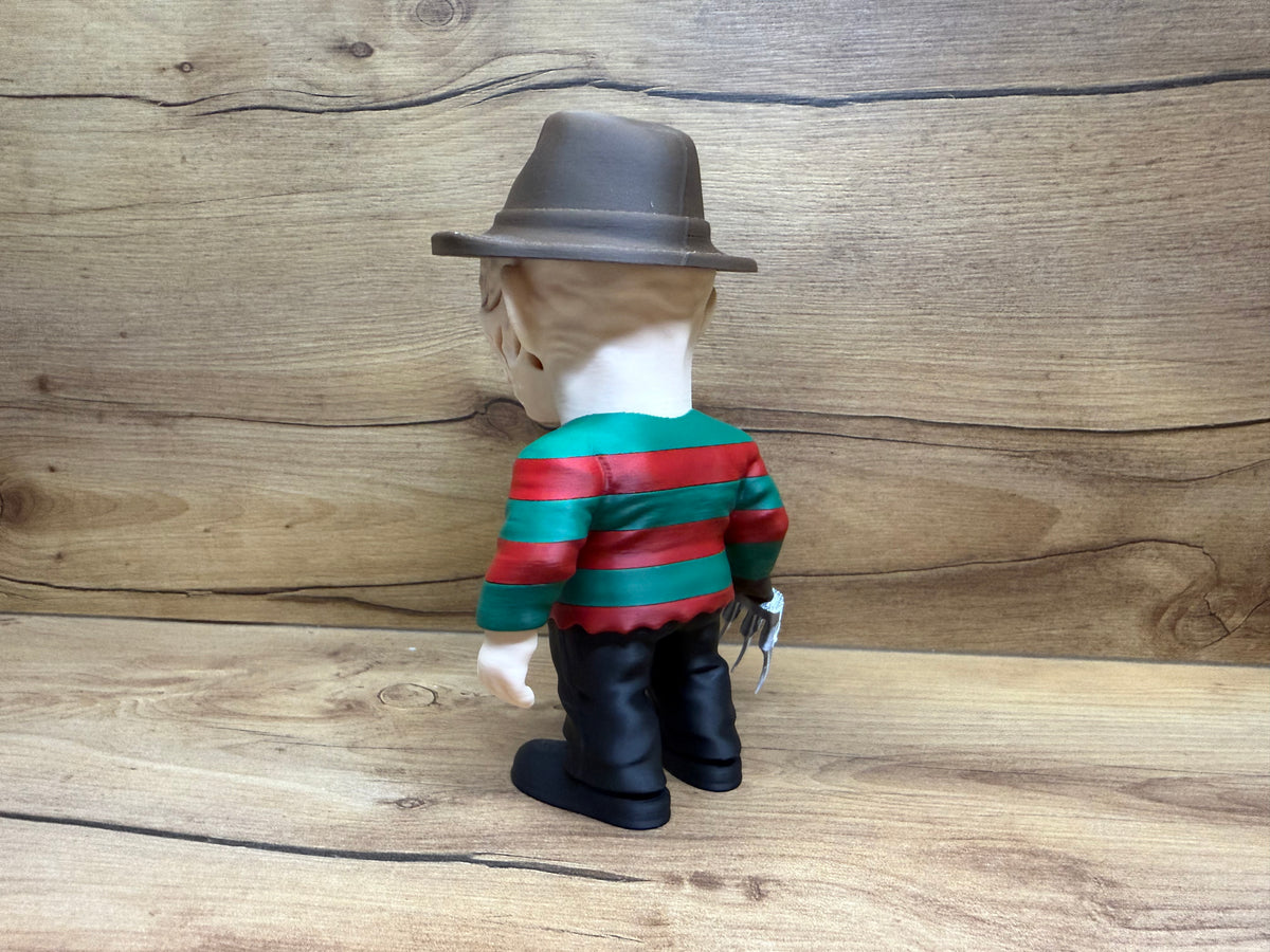 Freddy Krueger Nightmare on Elm Street Minifigure Sculpture — rear view showing fedora dome crown and full brim from rear, scarred face rear lower edge and bare neck, red and green stripe sweater rear panel with full alternating stripe detail, right razor glove visible at right side from rear, bare left hand at left side, black trouser rear and black boots from rear