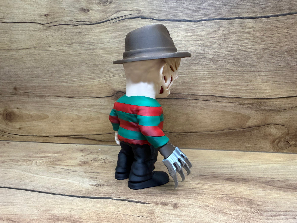 Freddy Krueger Nightmare on Elm Street Minifigure Sculpture — right rear three-quarter view showing fedora brim sweep from rear right angle, scarred face partially visible at rear three-quarter, red and green stripe sweater right side, right hand razor glove with four silver blades fanning outward clearly visible from rear three-quarter angle, left hand at side, black trousers and boots