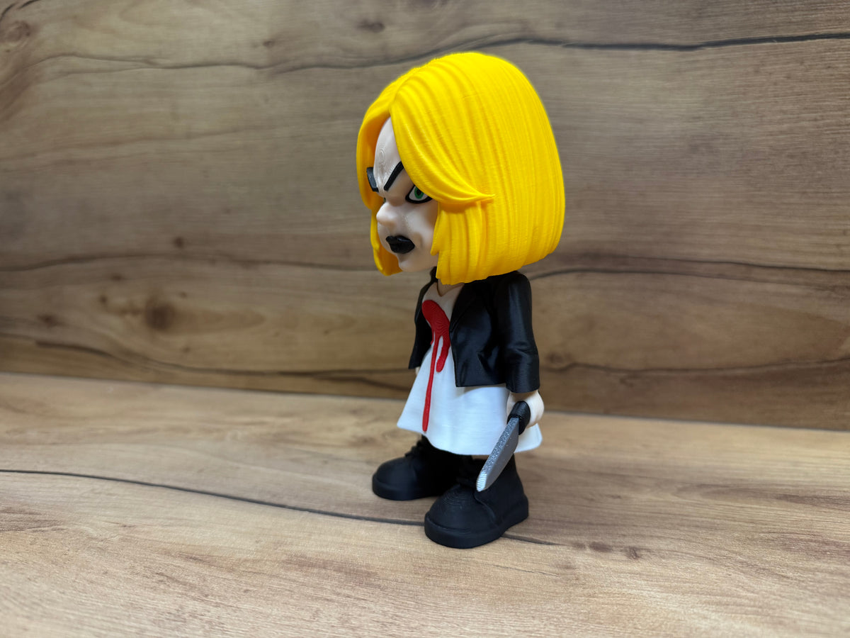 Tiffany Bride of Chucky Minifigure Sculpture — right side profile view showing full yellow bob hair volume, side face with green eye and black brow, black leather jacket profile, white dress hem and knife held at side in right hand