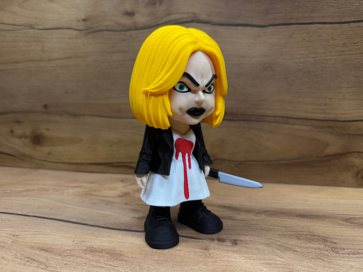 Tiffany Bride of Chucky Minifigure Sculpture — front three-quarter view showing fierce green eye and black brow expression detail, red dripping heart blood stain on white dress, open leather jacket lapels and silver kitchen knife at side