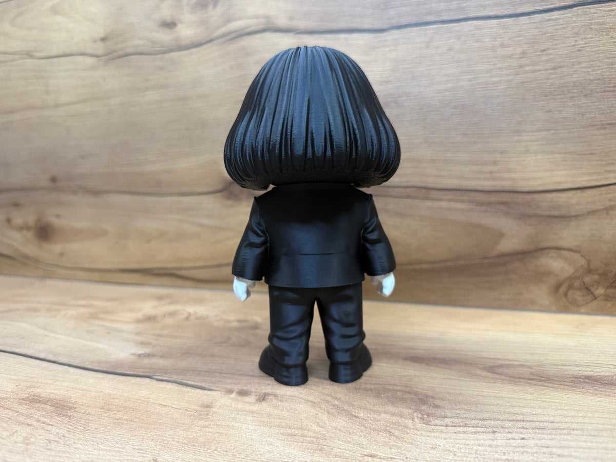 Billy the Puppet Saw Minifigure Sculpture — right side profile view showing white face profile with forehead wrinkle texture, right red spiral cheek rosette, single red-ringed eye, black bob hair side fall, red bow tie side and full black suit profile