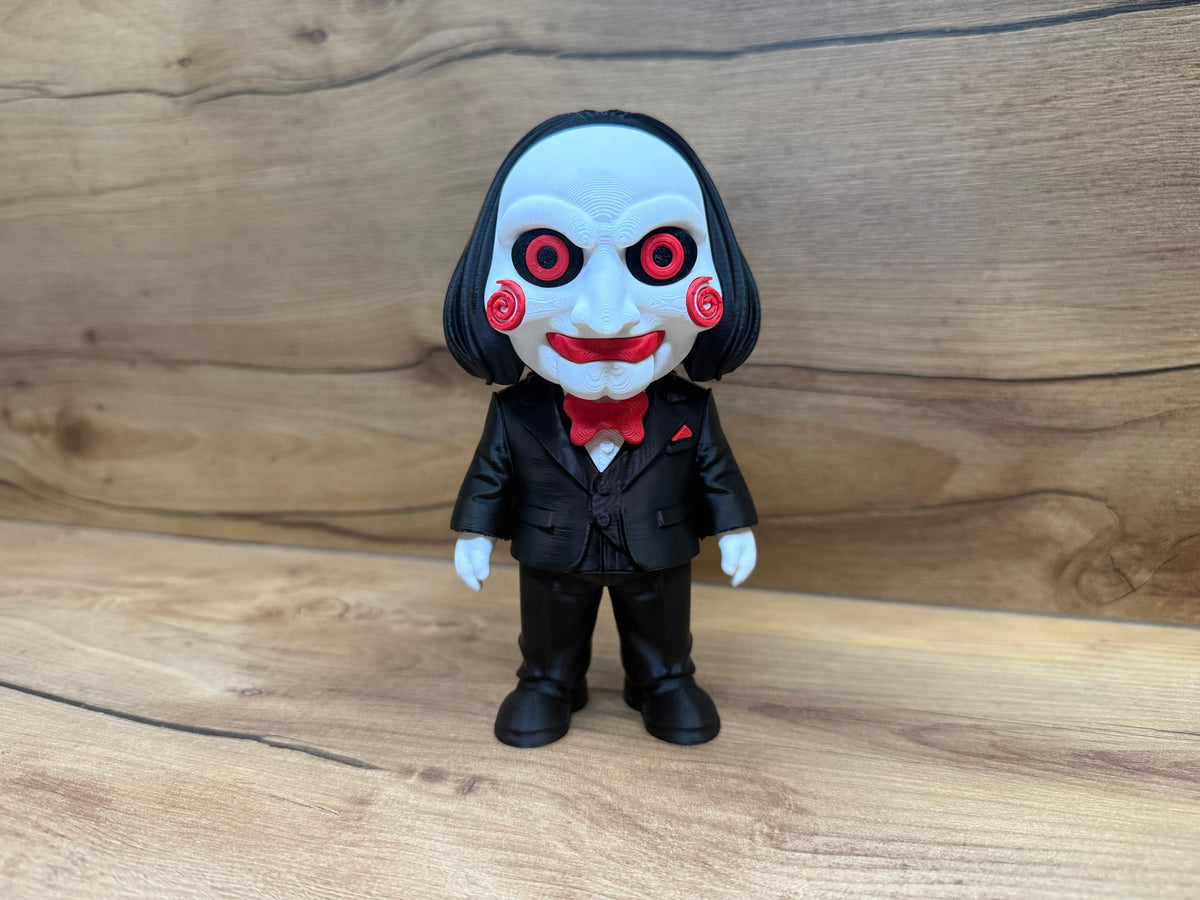 Billy the Puppet Saw Minifigure Sculpture — front three-quarter view showing full face detail including red spiral cheek rosettes, red-ringed eyes, open grin with teeth, forehead wrinkle lines, black bob hair, red bow tie and black formal suit with front buttons