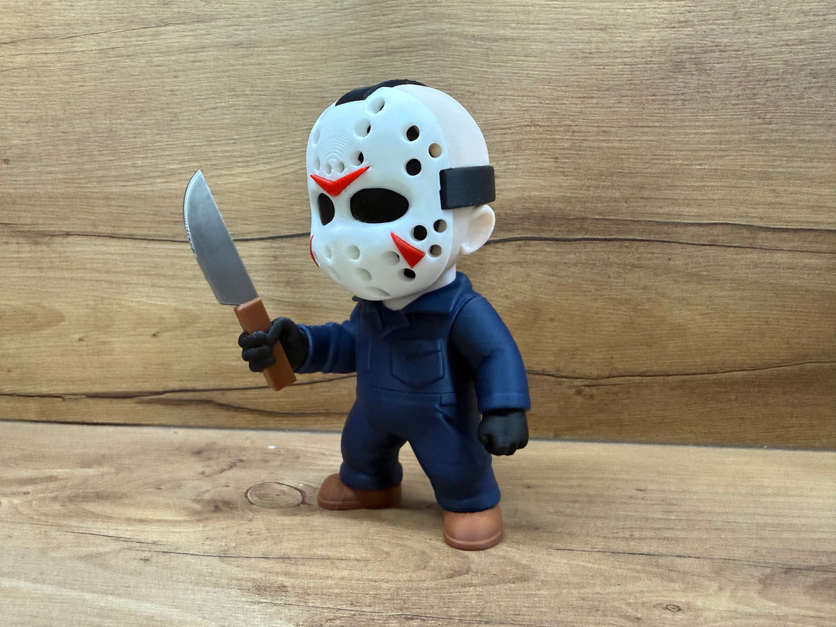 Jason Voorhees Friday the 13th Minifigure Sculpture — left front three-quarter view showing hockey mask at angle with red chevron and cheek accents visible, black crown strap, navy coverall left breast chest pocket, left black glove at side and silver cleaver raised in right hand with brown handle