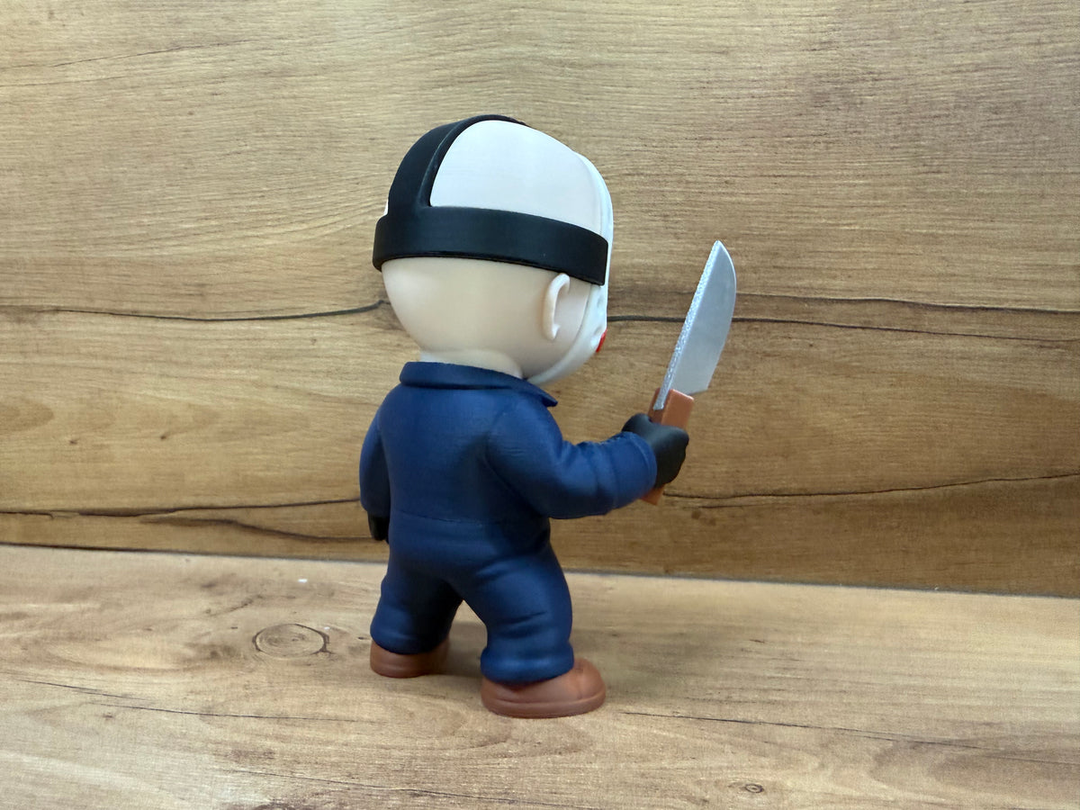 Jason Voorhees Friday the 13th Minifigure Sculpture — right side rear three-quarter view showing hockey mask profile with black crown strap, navy blue coverall rear panel seam lines, right arm extended holding silver cleaver blade rearward, brown work boot side profile