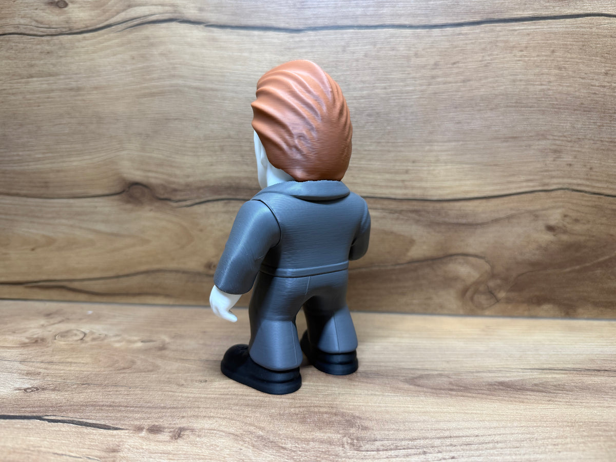 Michael Myers Halloween Minifigure Sculpture — rear view showing full auburn hair mass with individual strand texture swept back across crown and flowing down behind mask, dark charcoal grey coverall rear panel with seam lines, white left hand relaxed at side and black boot rear view