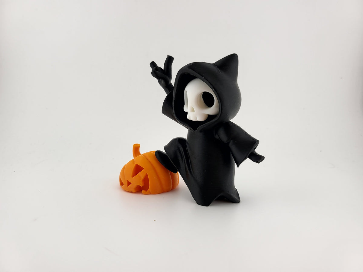 Halloween Reaper Cat Skull Minifigure — left three-quarter view: cat ear hood points from left angle, white skull face with oval void eyes, black robe drape, devil horn right hand raised, left arm extended, orange jack-o'-lantern pumpkin with triangle eyes nose and wide carved grin beside figure