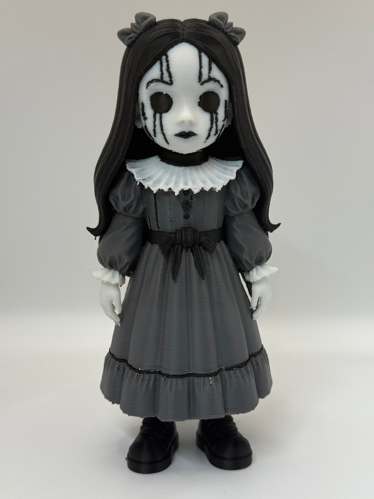 Gothic Doll Horror Minifigure Sculpture — front three-quarter view variant C showing full figure slightly turned, revealing depth of white ruffled collar, dress bodice panel detail, puffed sleeve form, waist sash bow and double-tiered skirt fall with black trim lines at tier division and hem