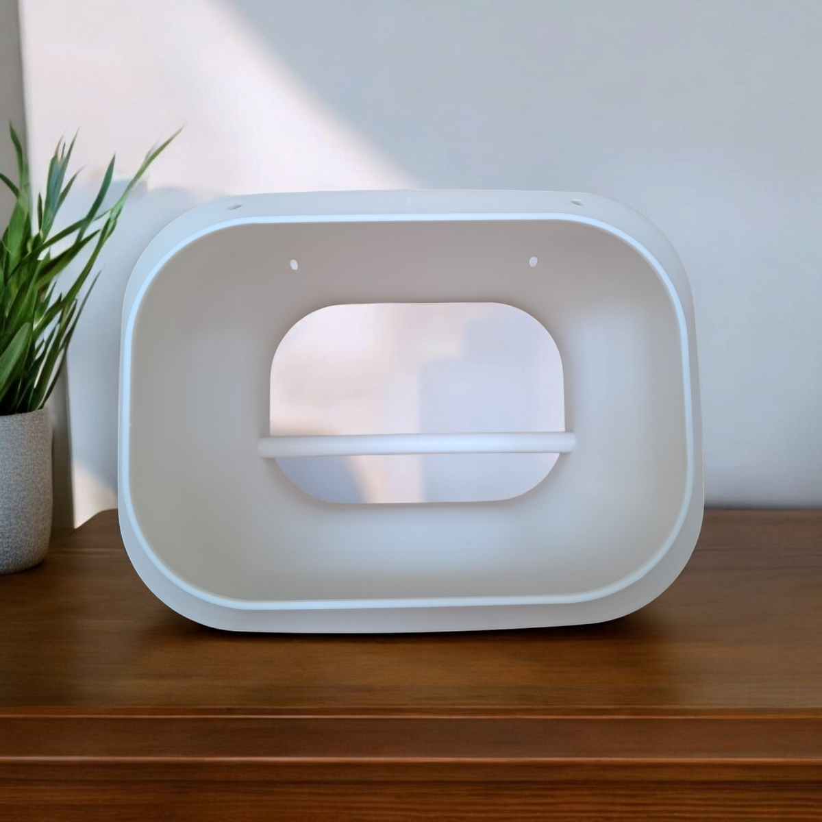 Modern white bird feeding station on wooden surface indoors with plant