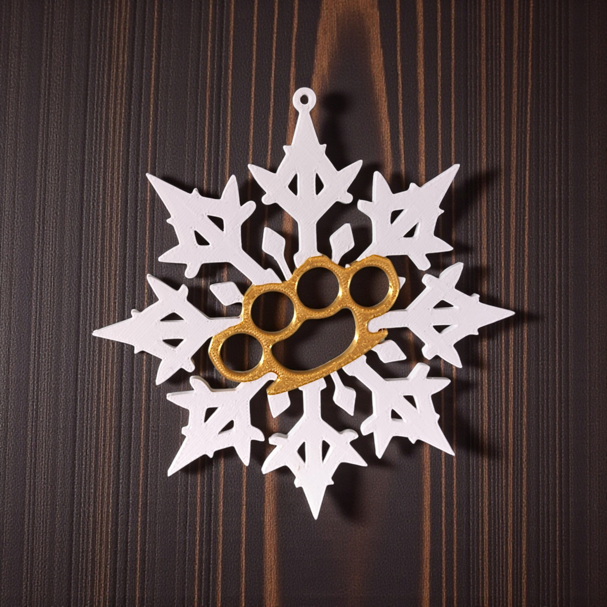 White and gold Bad Snowflake ornaments flat lay on dark wood surface