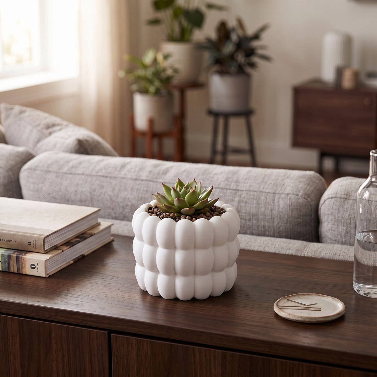 Bubble Plant Pot in white with green succulent on a dark wood surface beside a journal and brass watering can in a warm neutral modern interior with soft window light and linen throw chair