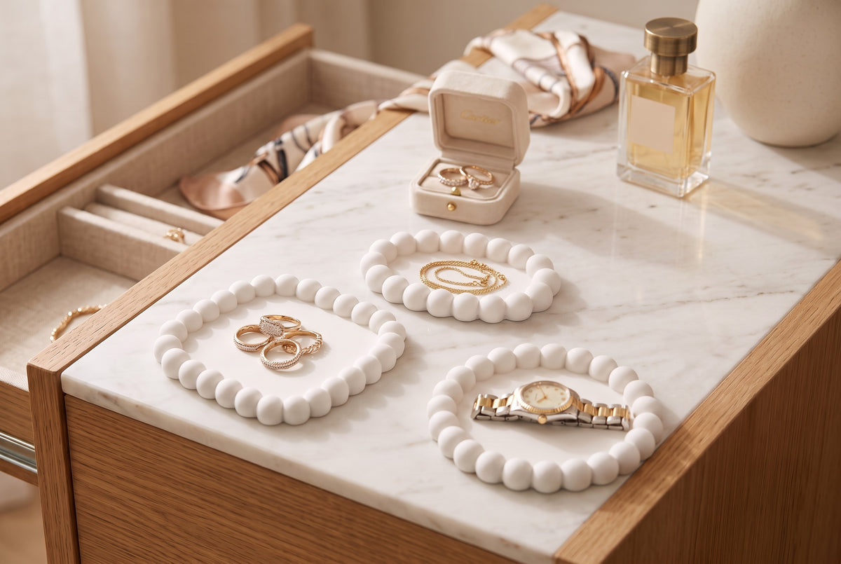 White round bubble tray with gold rings and a necklace on a grey dresser