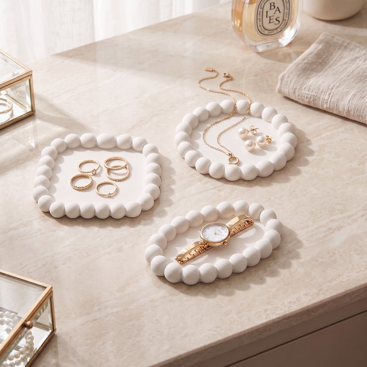 Three white bubble trays on a stone plinth with jewellery and a lamp in the background