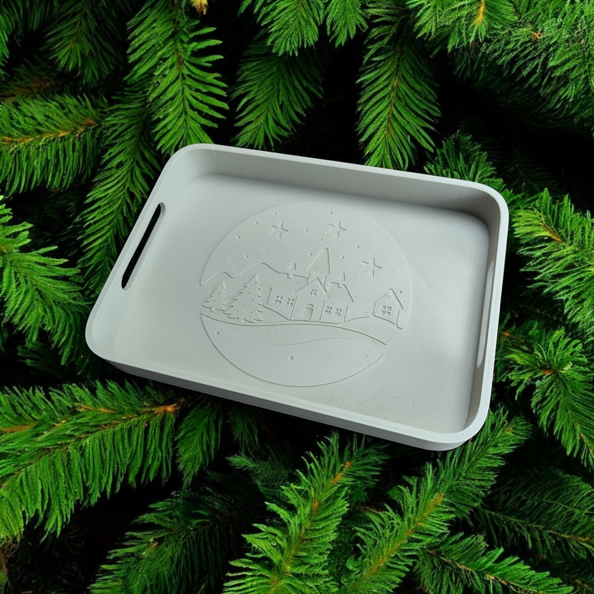 Winter village tray on dark wooden table surrounded by pine branches fairy lights and pine cones overhead