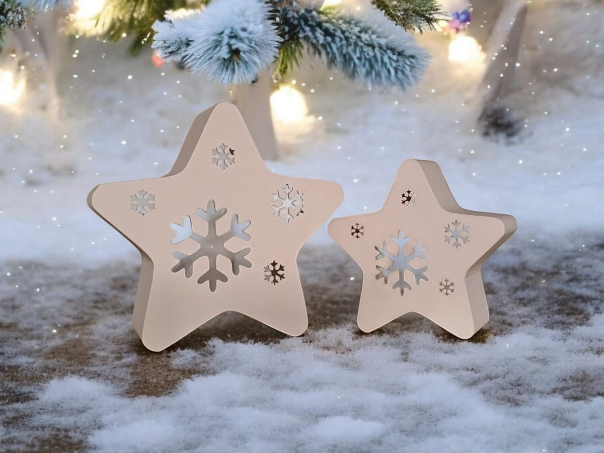 Two white star snowflake tealight holders on table with fairy lights bokeh neutral background