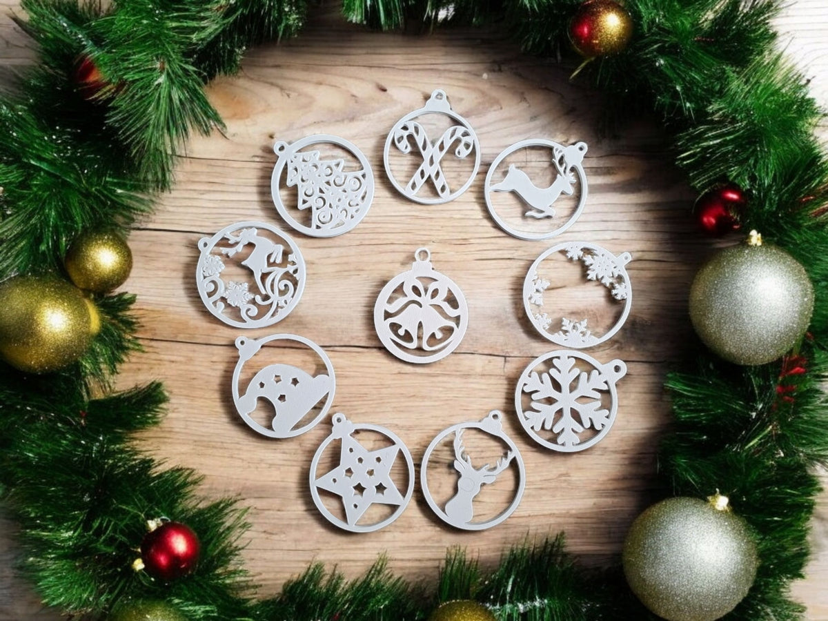 Four white plastic filigree Christmas bauble ornament hangers on warm oak wood Christmas garland gold baubles pine needles showing bells bow star snowflake designs festive flat lay