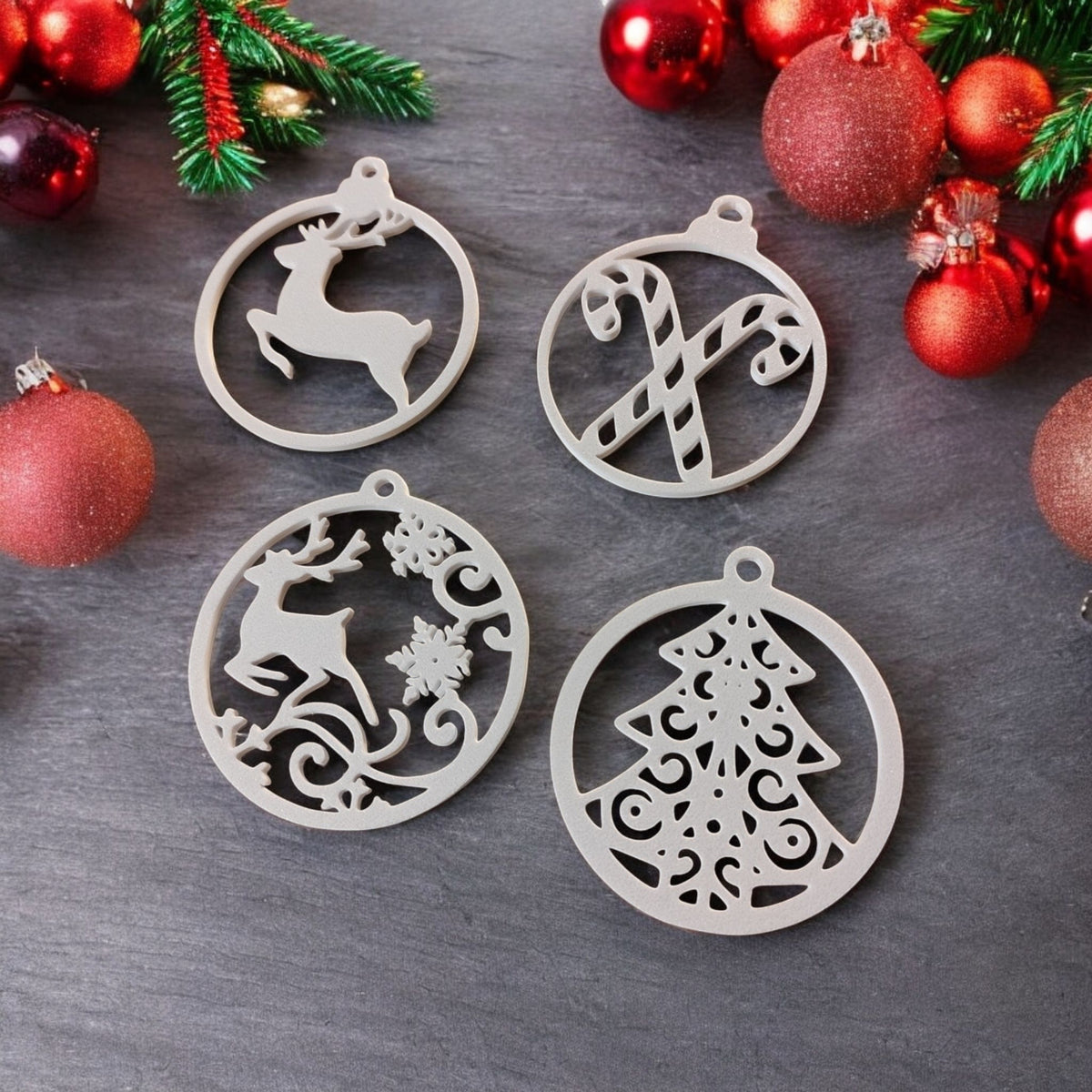 10 piece Christmas tree ornament hanger set white plastic filigree cut-out baubles arranged in Christmas tree pyramid shape on rich green draped fabric background all 10 designs visible overhead flat lay editorial