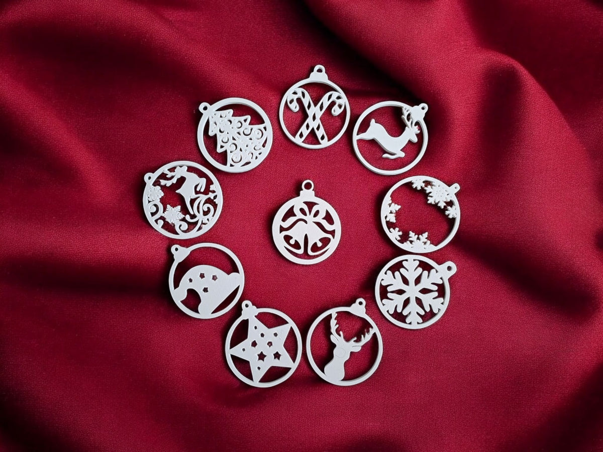 Four white plastic filigree Christmas bauble ornament hangers on warm oak wood Christmas garland gold baubles pine needles showing leaping reindeer candy cane snowflake wreath stag head designs festive flat lay