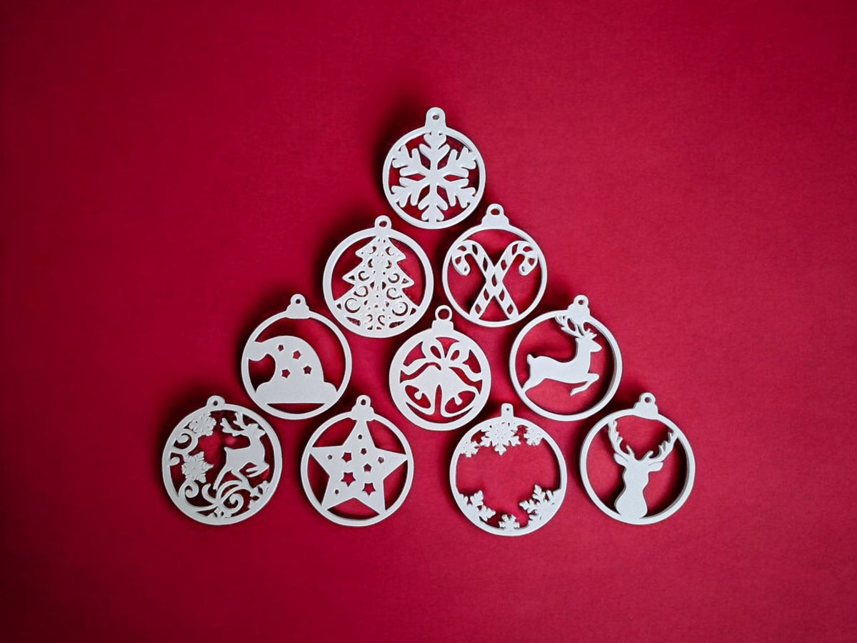 Two white plastic filigree Christmas bauble ornament hangers hanging from silver hooks warm Christmas market fairy lights bokeh background Christmas tree and snowflake designs atmospheric warm amber festive glow