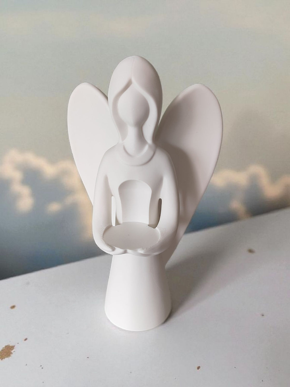 Back view of white angel sculpture on light wooden surface minimalist clean
