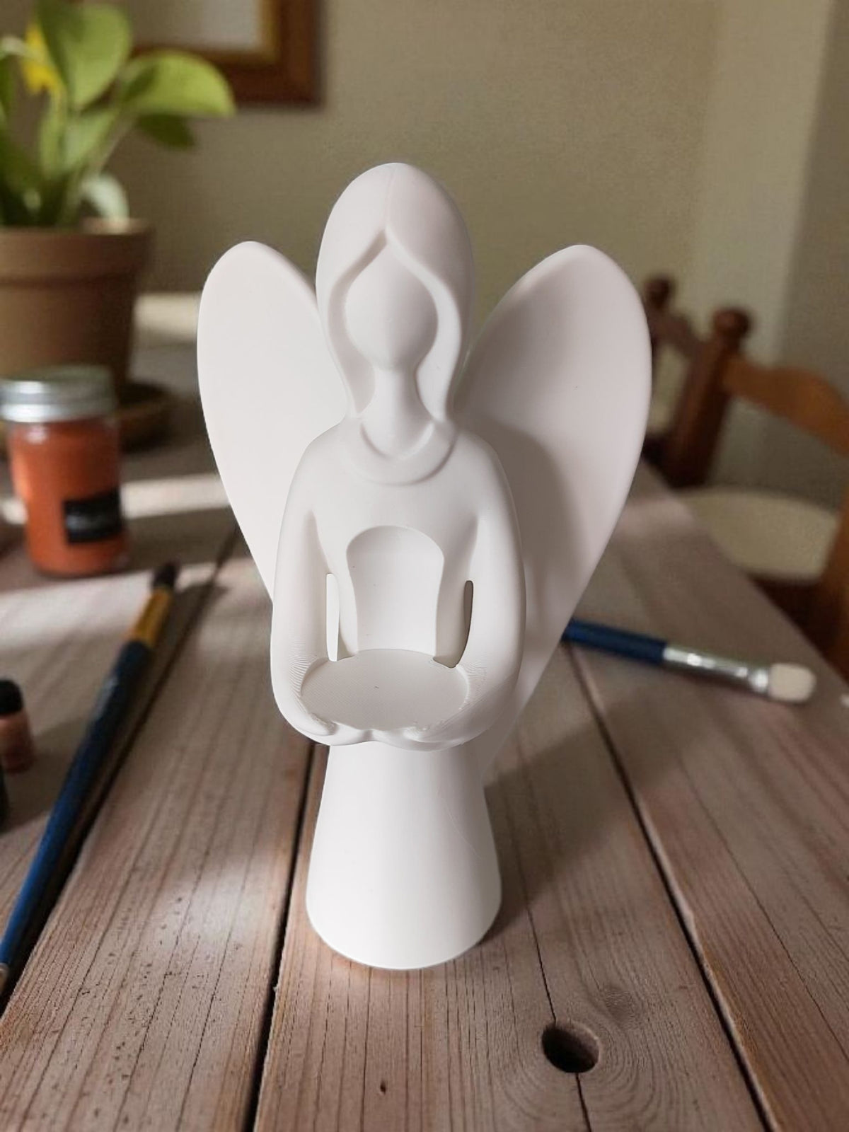 Front view of white angel sculpture on wooden table light background