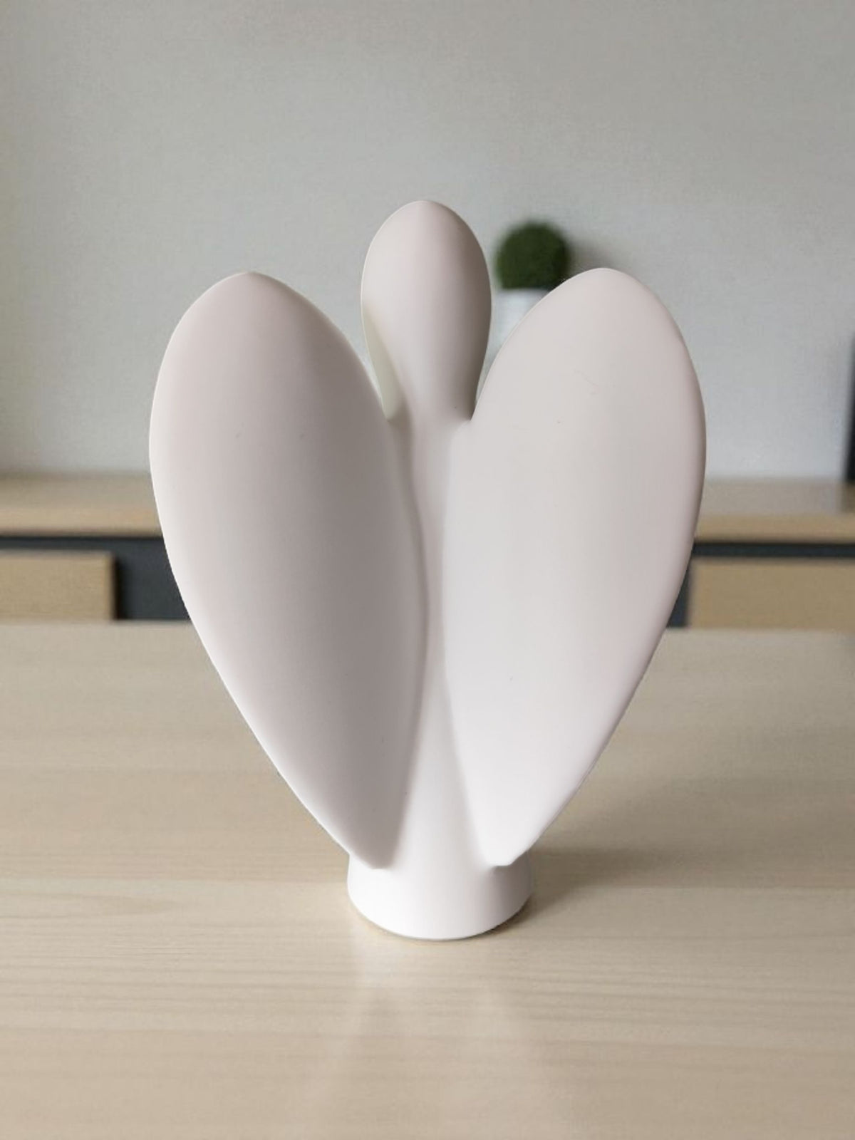 Three quarter view of white angel sculpture on white surface clean background
