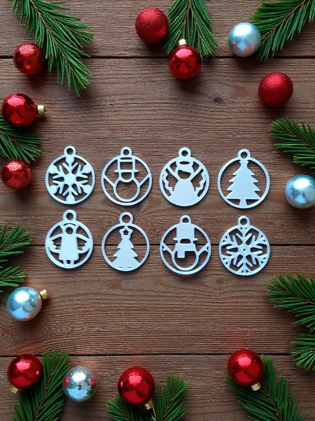 Three white minimalist Christmas ornaments on wooden table with pine sprigs and tealight — tree, snowman, star designs