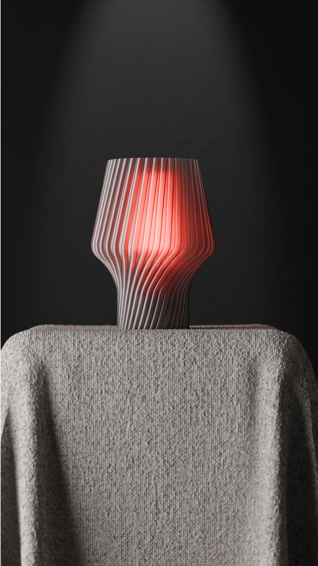 Twist Form Table Lamp grey ribbed twist silhouette warm red glow held in two hands dark background portrait