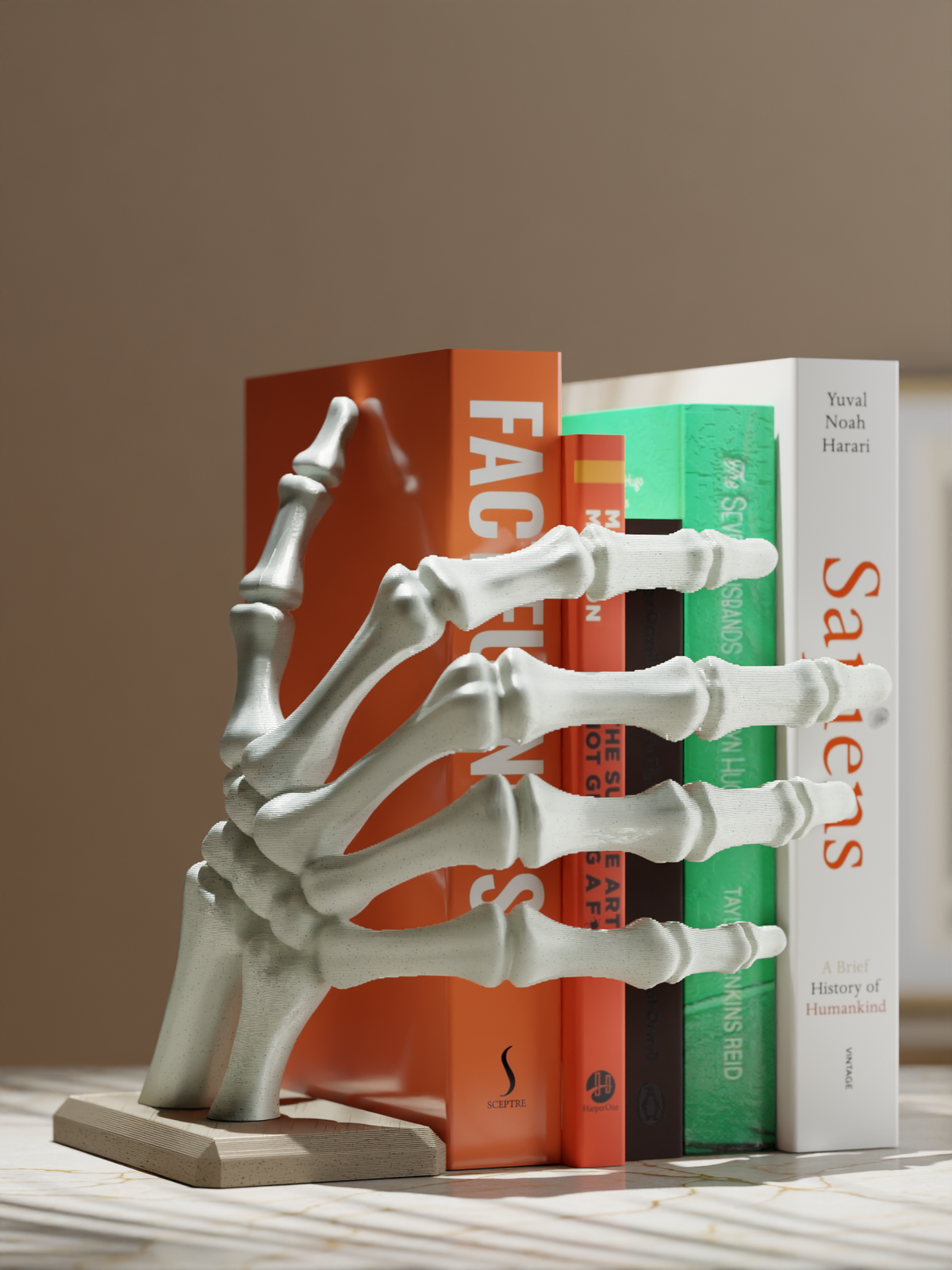 Bone-coloured skeleton hand bookstop supporting books on a shelf