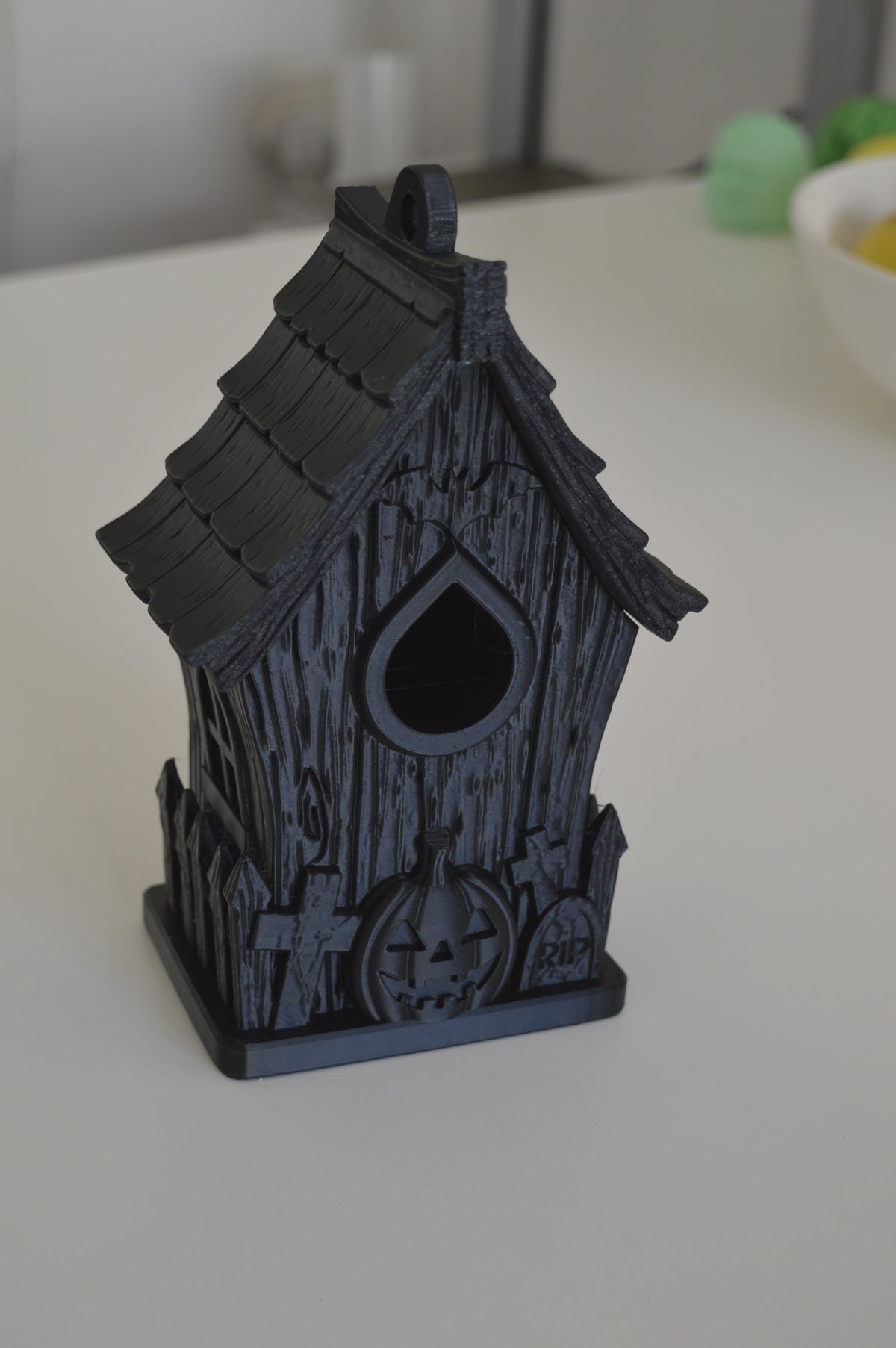 Front view of dark haunted bird house with pumpkin and gravestone