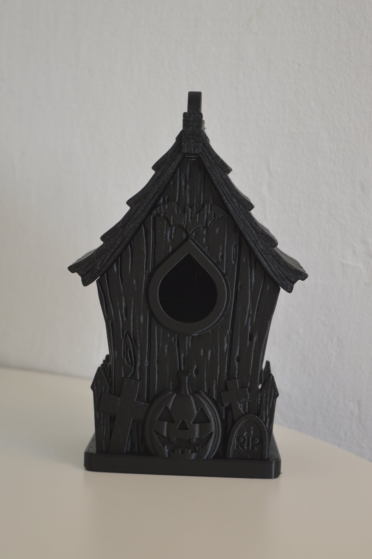 Close-up of haunted bird house shingled roof and hanging loop