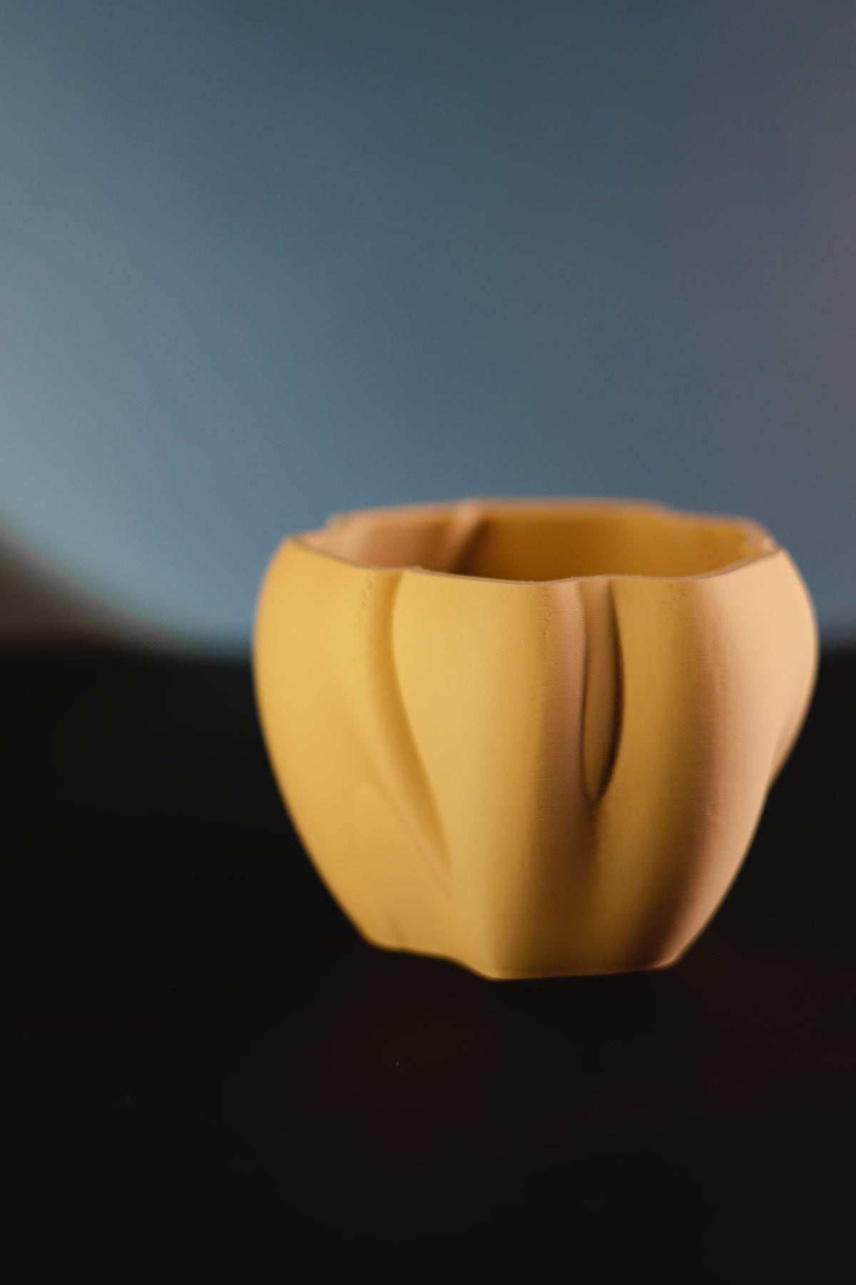 Elegant organic flowing planter yellow matte angled view showing petal lobe form on dark surface