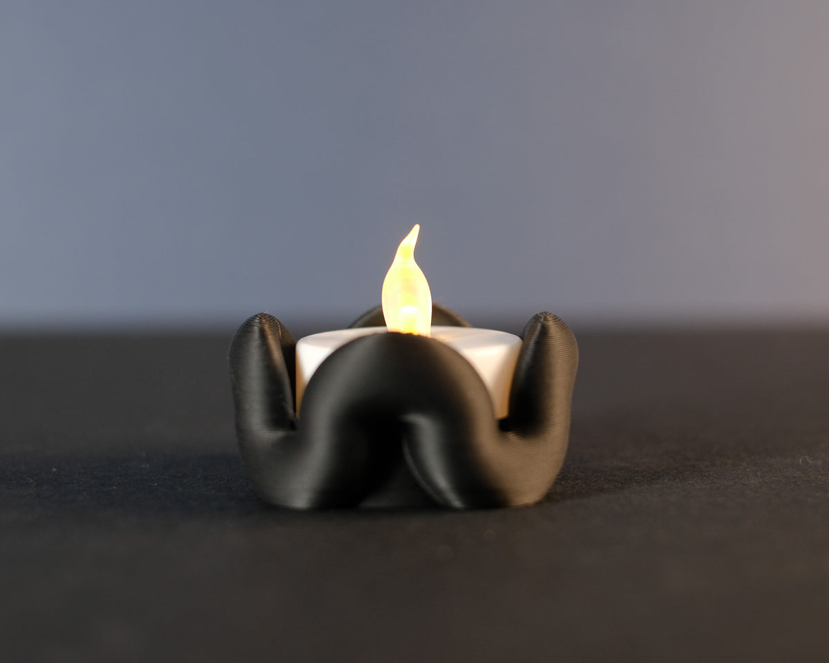 Wibble Tealight Holder - hand holding black version with lit tealight