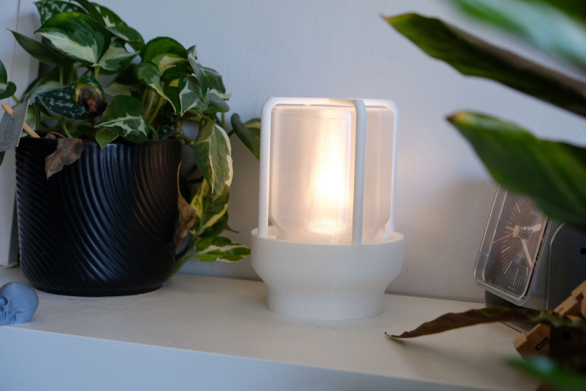The Miner's Lantern Lamp real photo white three quarter view shelf with plants warm amber glow soft interior